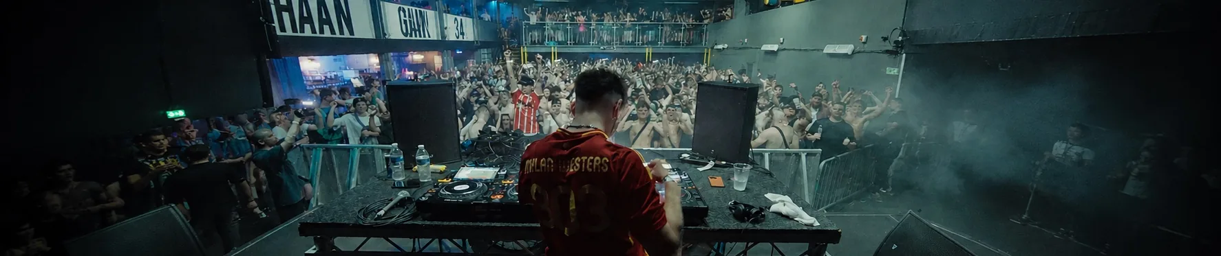 Mylan Westers behind the decks, seen from behind, facing a packed crowd
